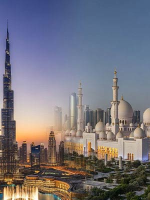 A grand white mosque with multiple domes and minarets stands beside a modern city skyline, including the Burj Khalifa, at sunset.